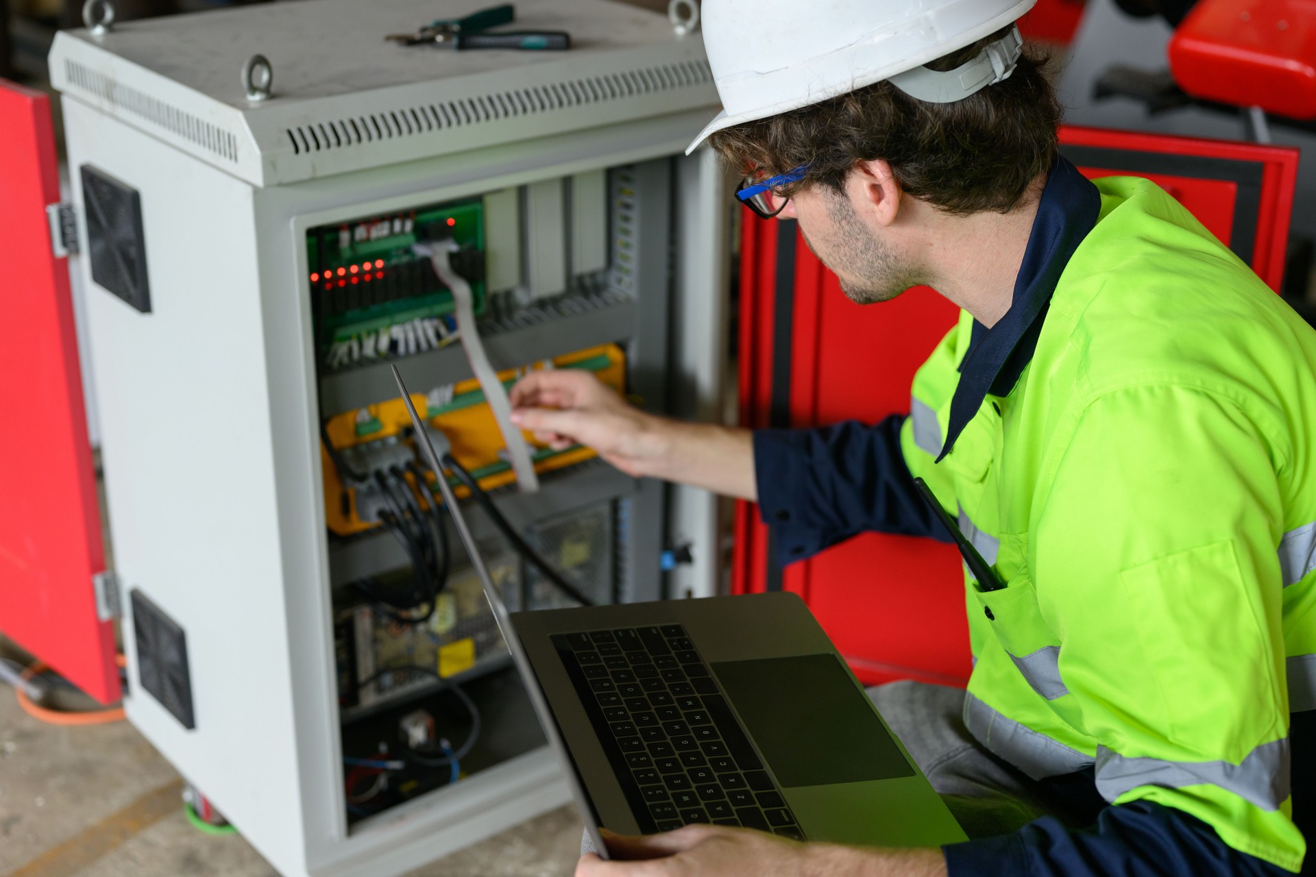 Trabalhador técnico profissional do sexo masculino no capacete branco verificando a manutenção da máquina no laptop na fábrica